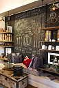 industry-home; chalkboard wall behind shop display. Such a cool industrial look behind shelving & would work at home as well!